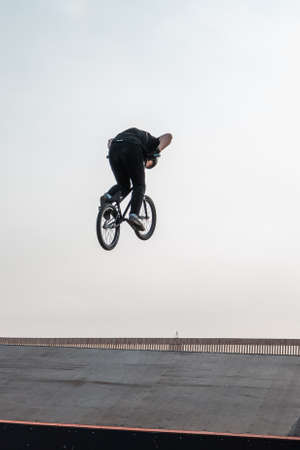 Kazan, Russia - September 26, 2020: A young rider on a BMX bike does tricks in the air. BMX freestyle in a skate park.のeditorial素材