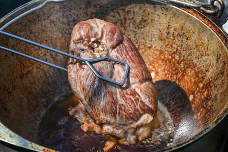 A piece of meat is fried in boiling oil. Cooking pilaf in a cauldron, a step-by-step recipe for real pilaf.の写真素材