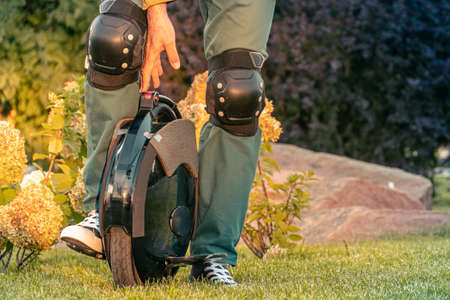 Rider's legs in protective gear on an electric unicycle (EUC). Driving around the city on an...