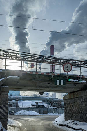 Smoking pipes of a thermal power plant behind an old railway bridge in an industrial area of the...
