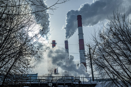 Smoking pipes of a thermal power plant behind an old railway bridge in an industrial area of the...