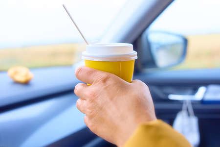 Woman holding a cup of coffee in the carの写真素材