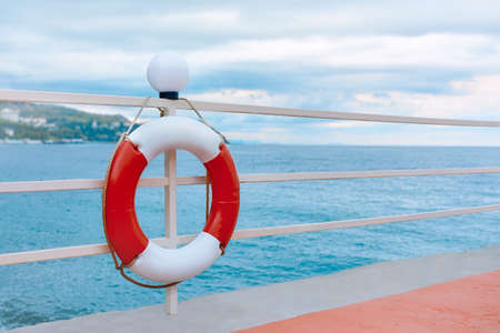 Lifebuoy hangs on the fence against the background of the sea.の写真素材