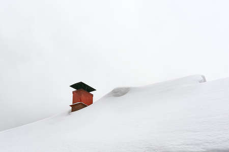 Brick chimney on a snow-covered roof.の写真素材