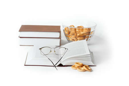 An open book with lying glasses on the pages and dryers. Still life with a book on a white background.の写真素材