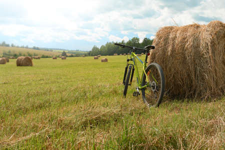 A bicycle by a stack in a field with mowed grass. Summer cross-country bike ride. Rest after a bike...