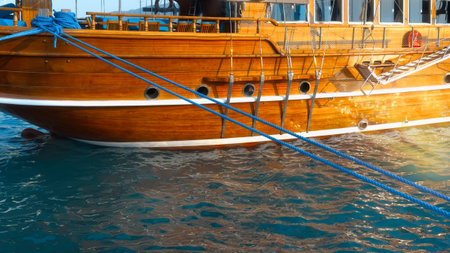 View of the moored ship. Beautiful wooden board of the ship in the light of the sun. Reflections in the water.の写真素材