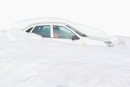 Passenger car completely covered with snow on a white background. Car in a snowdrift close-up.の写真素材