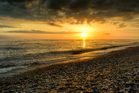 Seashore in the colors of the setting sun. Sunset over the Black Sea. Pebbles on the seashore.の写真素材