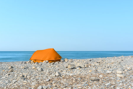 Lonely tent on the seashore. Summer holiday on the pebble seashore.の写真素材