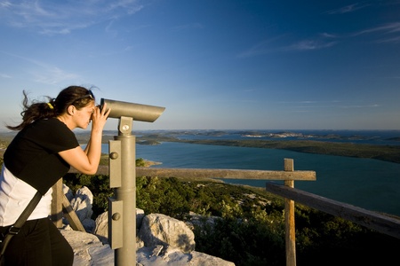 Woman looking through the telescope on te Vrana lake and islandsのeditorial素材