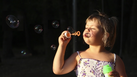 Little girl having fun with soap bubbles      の写真素材