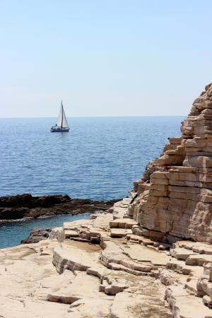 White sailboat passing by the cliffの写真素材