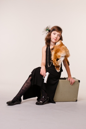 A girl dressed as a gangster. He sits on the box. In a hand gun in the neck skin is lesitsyの写真素材
