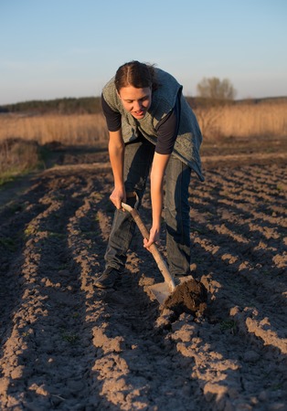 Female farmer works with manure at field, holding agricultural toolsの写真素材