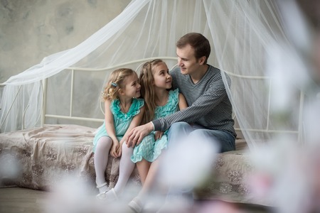 Over head view of a young pregnant mother and her young toddler daughter being playful in bed and having fun while at home, interior.の写真素材