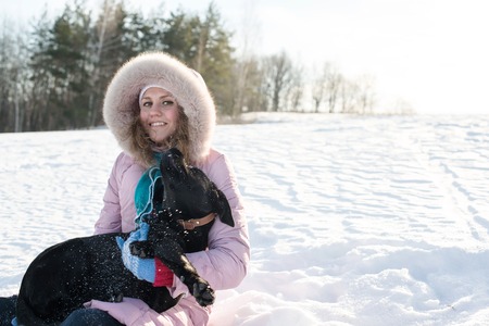 Girl with her cute dog in the winter forestの写真素材
