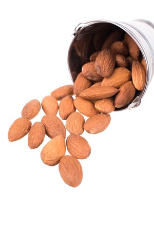 Tin bucket full of almonds isolated on white background.の写真素材