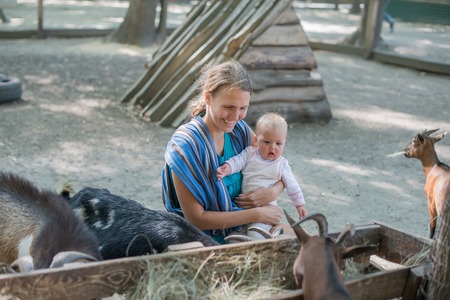 Happy mother and her daughter with baby goats on the countrysideの写真素材