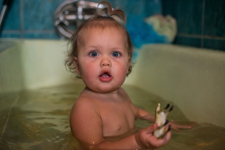 Cute little girl in the bath with a red soap