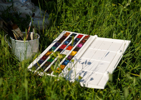 Palette of watercolors and brushes on the green grass.の写真素材