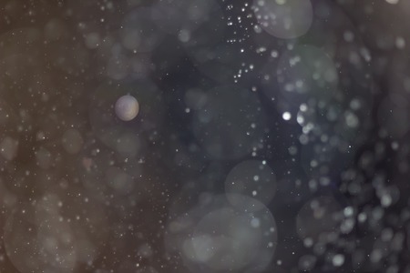 Dark abstract background with sparkling white snowflakesの写真素材