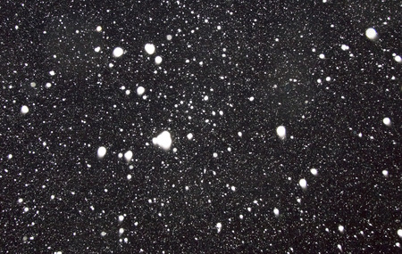 White flakes of snow on a black background. It is possible to use as a backgroundの写真素材
