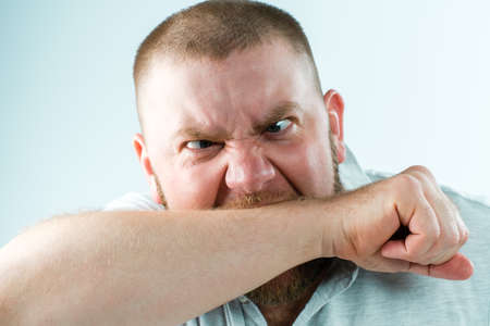 Angry man bites himself by the handの写真素材