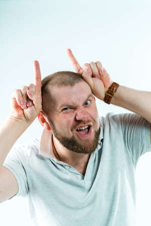 A handsome man has put his fingers as horns at the devilの写真素材