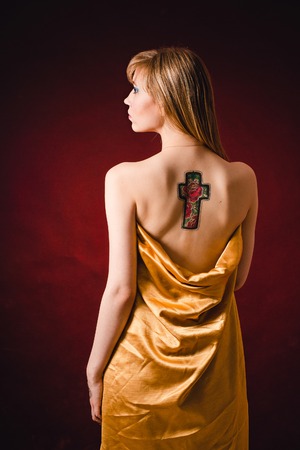Beautiful girl with a tattoo on her back  on a dark backgroundの写真素材