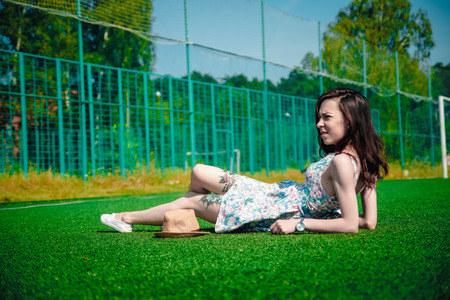 Beautiful young girl in a dress posing at the stadiumの写真素材