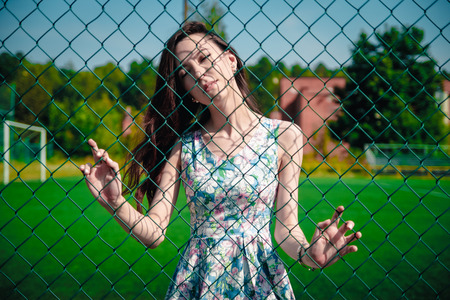 Beautiful young girl in a dress posing at the stadiumの写真素材
