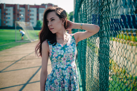 Beautiful young girl in a dress posing at the stadiumの写真素材