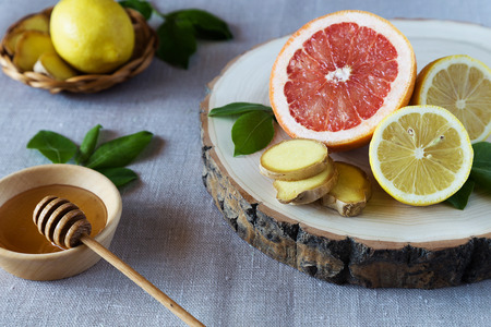 Grapefruit, lemons and ginger on a wooden stand with a plate of honeyの写真素材