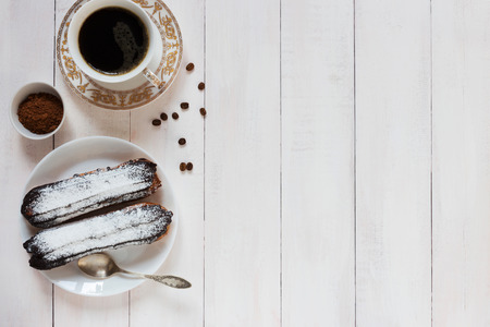 A horizontal photo of two chocolate eclairs and coffee beansの写真素材