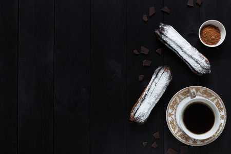 A horizontal photo of two chocolate eclairs and a cup of coffeeの写真素材