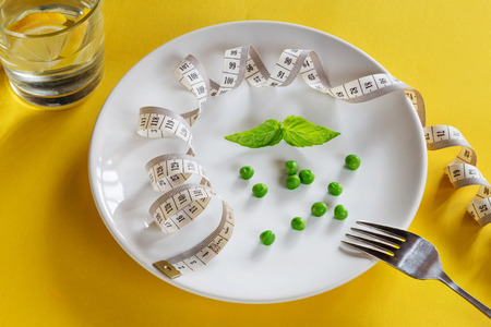Horizontal photo of white plate with centimeter, peas and basilの写真素材