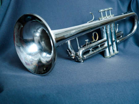trumpet on a gray background. the musical instrument is lying on the fabric.