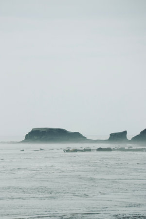 Foggy seascape with cliffs and rocks in the foregroundの写真素材