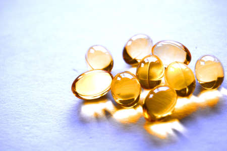 gold capsules of cod liver oil on background