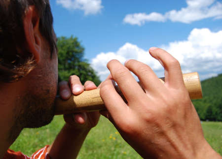 man plays flute in mountainsの写真素材