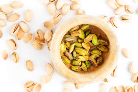Peeled pistachios in mortar on a white background. Flat.