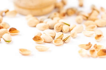 Peeled pistachios in mortar on a white background. Selective focus.