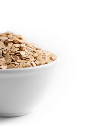 Frontal close up view of an oat flakes bowl isolated on a white background.の写真素材
