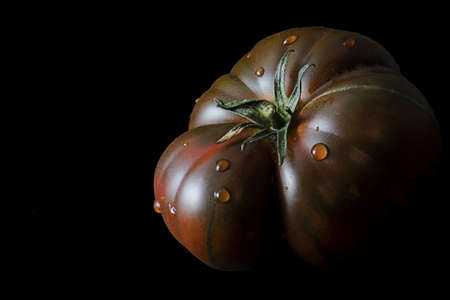 Close up shot of tomato photo stack with water drops on black backgroundの写真素材