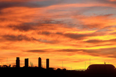 Sunset with silhouette of buildings with blue, orange and yellow skyの写真素材