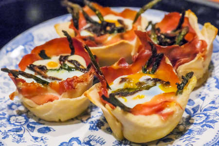 Close up of bread baskets with egg, bacon and wild asparagus on plate with black background