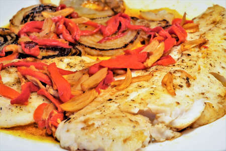 Close up of Hake fillets a la bilbaina on plate with bell pepper and garlicの写真素材