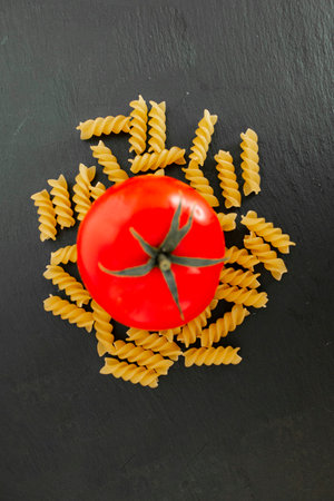 Whole red tomato with fusilli on black backgroundの素材 [FY310160772676]