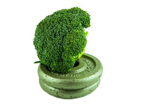 Sport and nutrition composition as a green broccoli next to a dumbbell isolated over white backgroundの写真素材